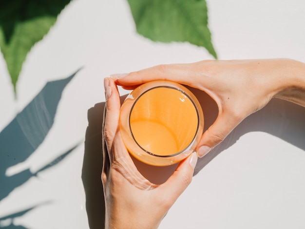 Vista superior do suco de laranja com mãos de mulher