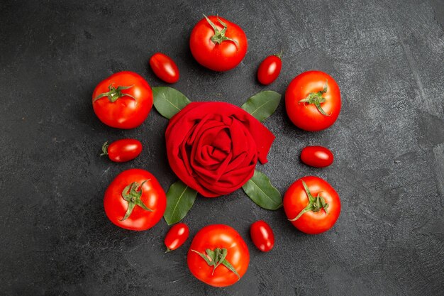 Vista superior do tomate vermelho e cereja em torno de uma toalha em forma de rosa e folhas de louro em um solo escuro com espaço de cópia