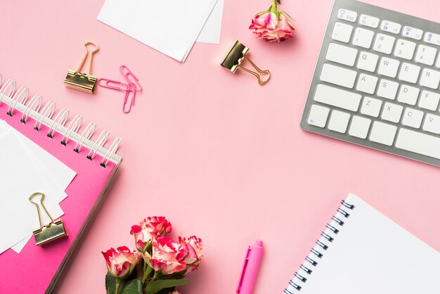 Vista superior dos artigos de papelaria de mesa com buquê de rosas