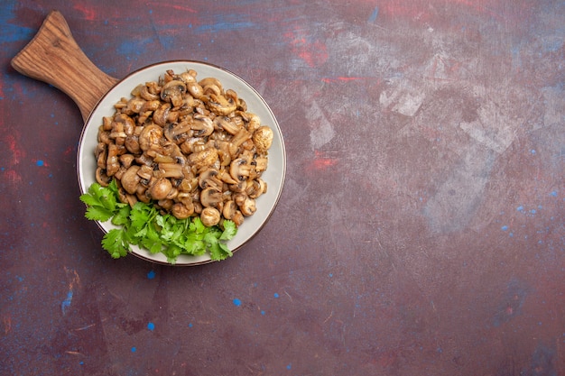 Vista superior dos cogumelos cozidos deliciosos com verduras no chão escuro