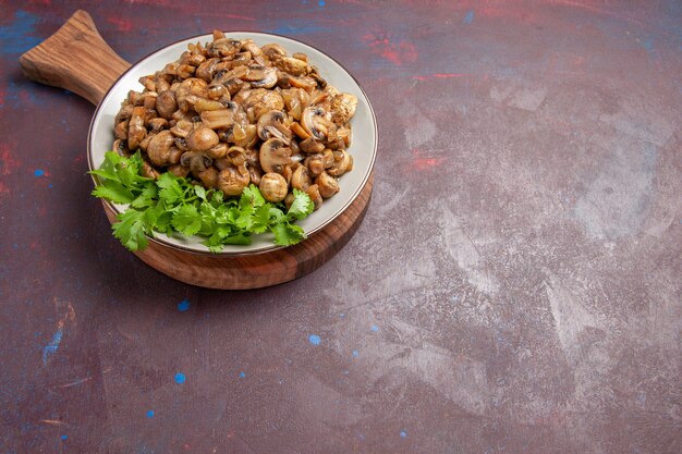 Vista superior dos cogumelos cozidos saborosos com verduras no escuro