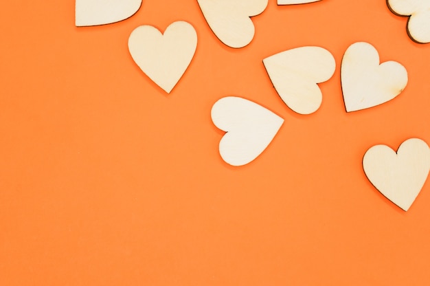 Foto grátis vista superior dos corações em forma de madeira na superfície laranja - espaço para texto