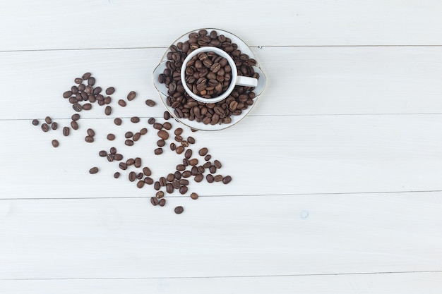 Vista superior dos grãos de café na xícara e pires em fundo de madeira. horizontal