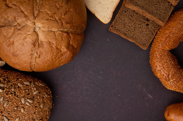 Vista superior dos pães como bagel de pão de sanduíche de espiga e centeio fatiado e pães brancos sobre fundo marrom com espaço de cópia