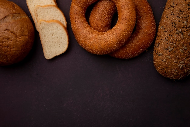 Vista superior dos pães como pão sanduíche de bagel de espiga e pão branco fatiado em fundo marrom com espaço de cópia