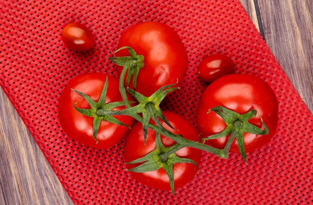 Vista superior dos tomates no pano vermelho e superfície de madeira