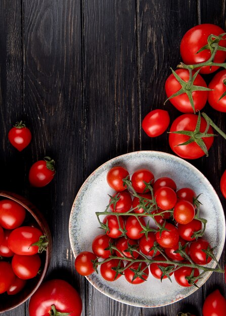 Vista superior dos tomates no prato e outros na superfície de madeira