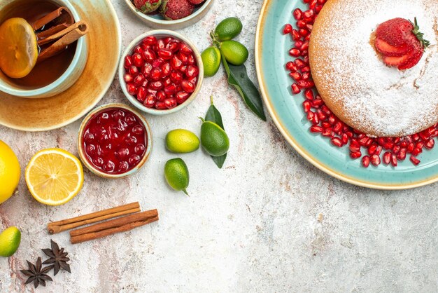 Vista superior em close-up com frutas e geléia de chá, canela, uma xícara de chá, o bolo com morangos