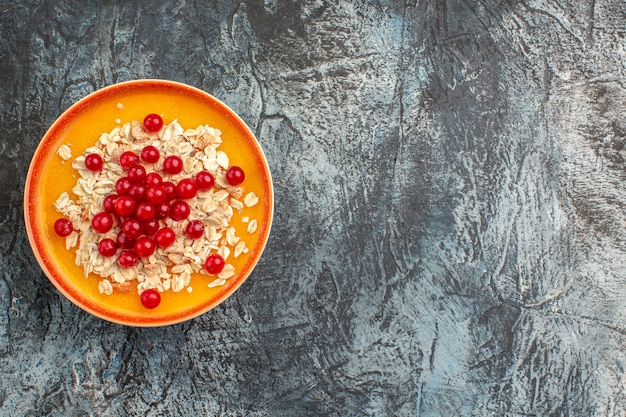 Vista superior em close-up com frutas, prato laranja de groselha na mesa cinza