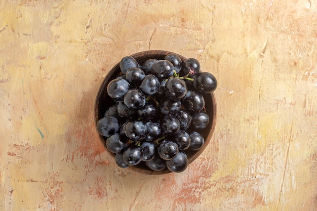 Foto grátis vista superior em close-up da tigela de uvas com cachos de uvas pretas na mesa de creme