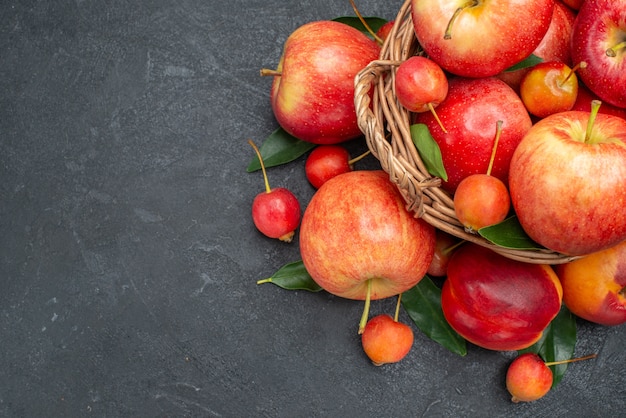 Vista superior em close-up de frutas, frutas vermelhas-amarelas e bagas com folhas na cesta