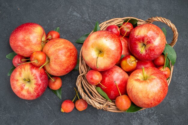 Vista superior em close-up de frutas, maçãs e frutas vermelhas com folhas na cesta