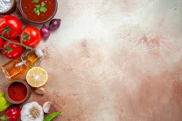 Foto grátis vista superior em close-up especiarias especiarias coloridas cebolas alho garrafa de óleo tomate molho de limão