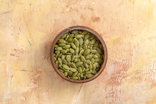 Vista superior em close-up tigela de sementes de abóbora descascadas na mesa