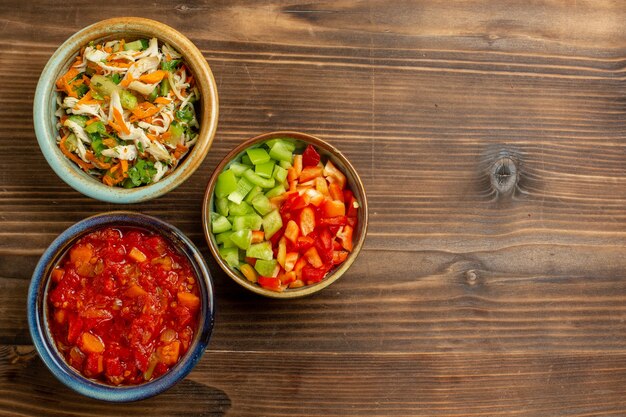 Vista superior fatiada de legumes com tomate no fundo de madeira marrom comida de vegetais salada saúde