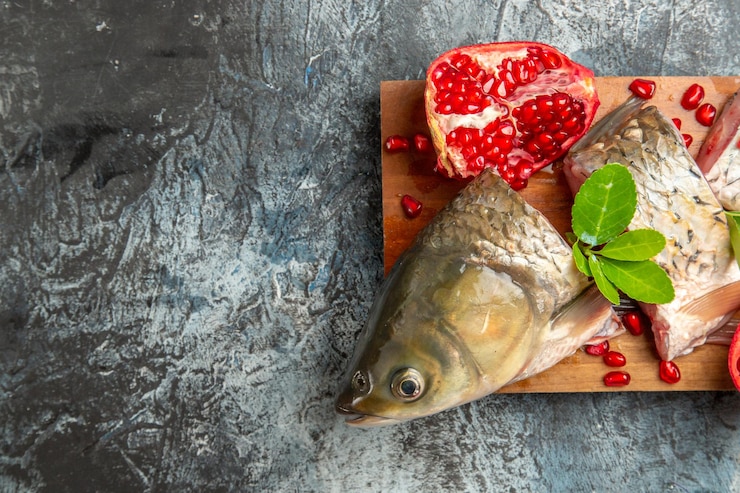 Foto grátis vista superior fatiada de peixe fresco com romãs na superfície claro-escuro