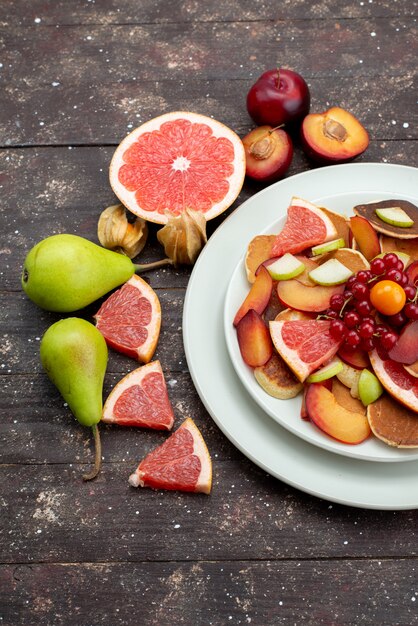 Vista superior fatiada frutas frescas maduras e maduras dentro de chapa branca