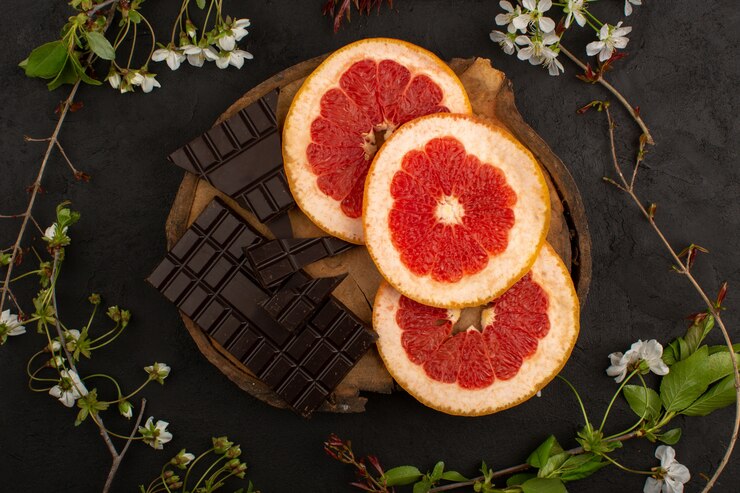 Foto grátis vista superior fatiadas de toranjas e barras de chocolate no chão escuro