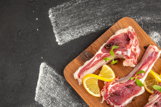 Vista superior fatias de carne crua com verduras e limão em fundo escuro carne frango salada vegetal vaca foto colorida animais