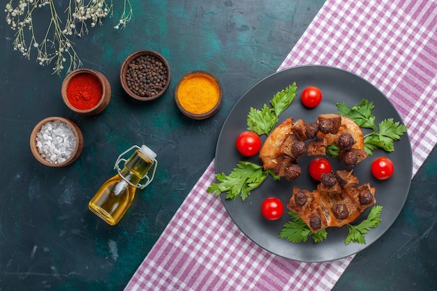 Vista superior fatias de carne frita com temperos verdes e tomate cereja em superfície escura