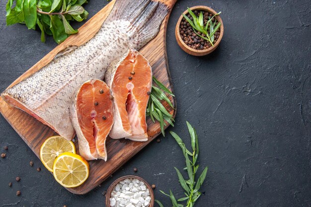 Vista superior fatias de peixe fresco com limão e verduras em fundo escuro frutos do mar saúde carne jantar oceano refeição restaurante comida