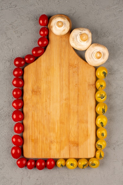 Foto grátis vista superior forrada de legumes como tomate vermelho amarelo e cogumelos no fundo cinza