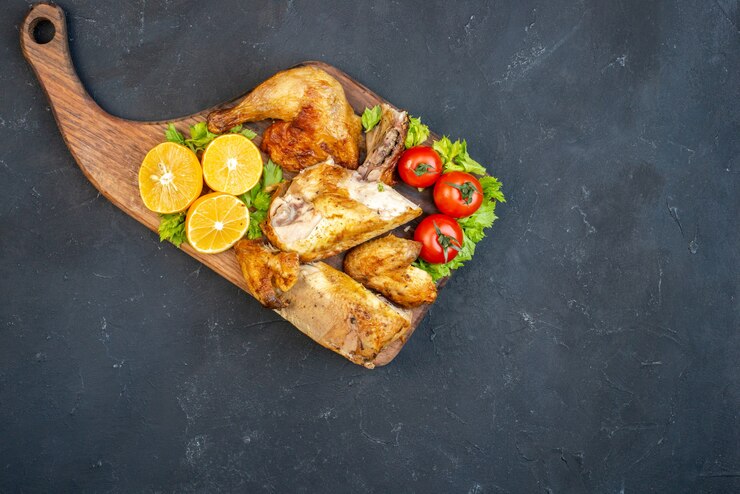 Foto grátis vista superior frango assado, tomate, fatias de limão na placa de madeira com a alça na mesa