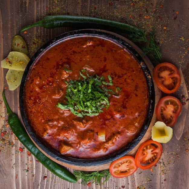 Vista superior kharcho com pimenta verde e tomate e verduras no prato escuro