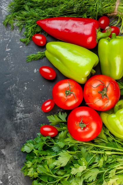 Foto grátis vista superior legumes frescos pimentões vermelhos e verdes tomates cereja salsa tomates em superfície escura