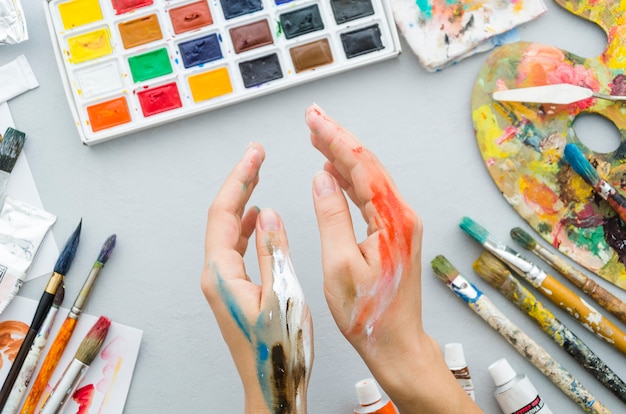 Vista superior mãos sujas com materiais de pintura