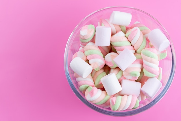 Vista superior mastigando marshmallows dentro de uma tigela redonda na mesa rosa
