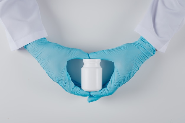 Foto grátis vista superior médico segurando o frasco de comprimidos com as duas mãos em branco