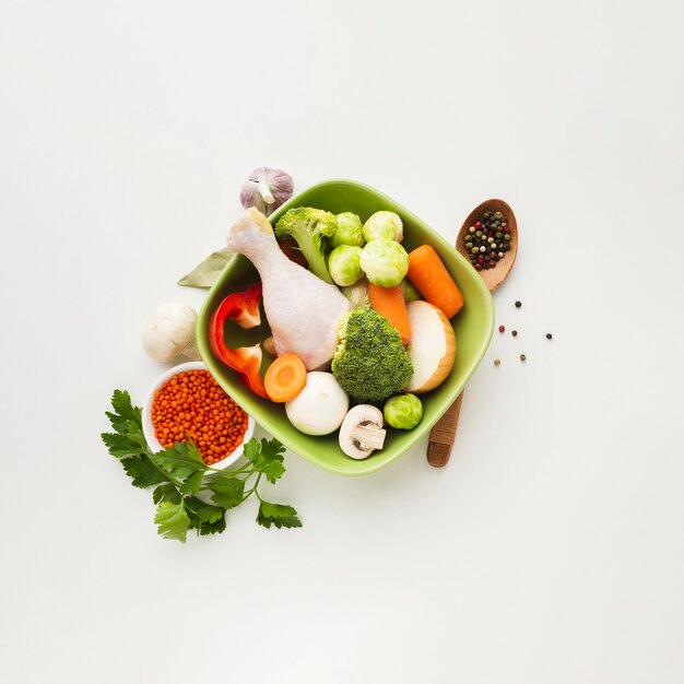 Vista superior mistura de legumes em uma tigela com coxa de frango
