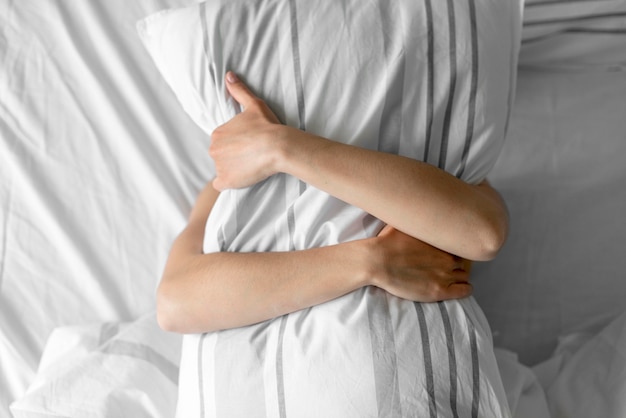 Vista superior mulher abraçando o travesseiro na cama