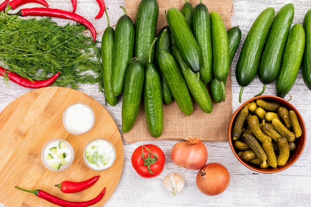 Vista superior pepino com endro cebola tomate pimenta no saco de linho bege com placa de corte em branco de madeira