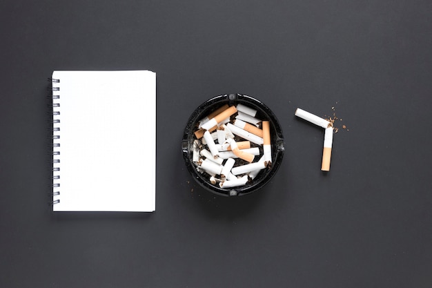 Vista superior pilha de cigarros com notebook