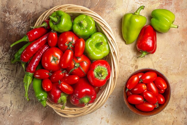 Vista superior pimentão verde e vermelho pimentão tomate na cesta de vime tomate cereja em uma tigela e pimentão no fundo âmbar