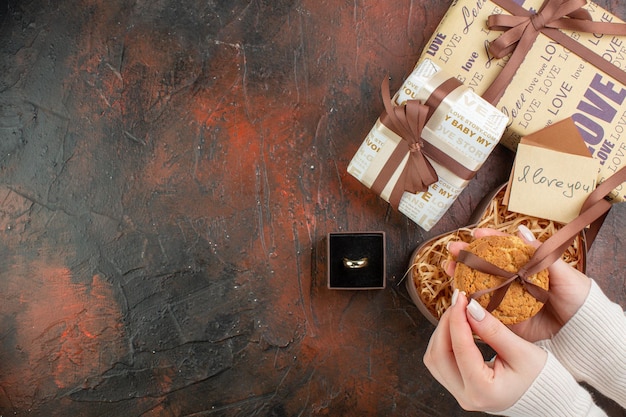 Vista superior presentes de dia dos namorados com anel e biscoitos em um fundo marrom escuro amor cor presente sentindo casamento casal de férias