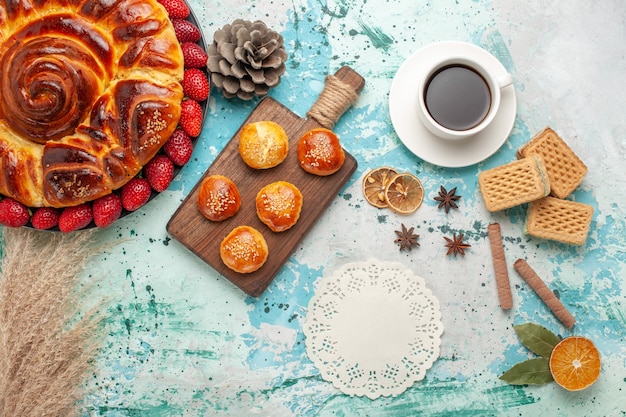 Vista superior redonda deliciosa com bolos de morangos vermelhos frescos e uma xícara de chá na superfície azul