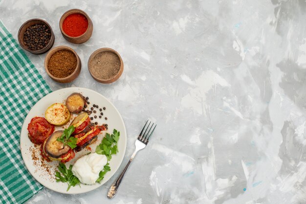 Vista superior refeição de vegetais cozidos dentro de um prato branco com temperos na mesa brilhante prato de refeição de comida vegetal