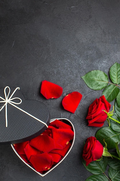 Vista superior rosas vermelhas com caixa cheia de pétalas de rosa para dia dos namorados em fundo escuro amor coração casal cor paixão sentimento
