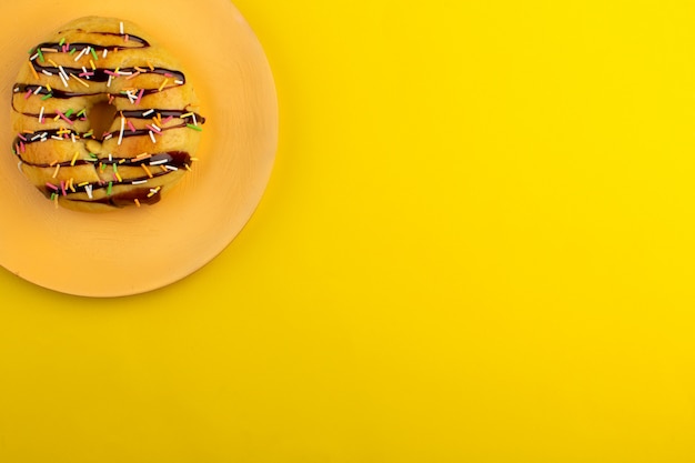 Vista superior rosquinha gostoso dentro placa laranja na mesa amarela