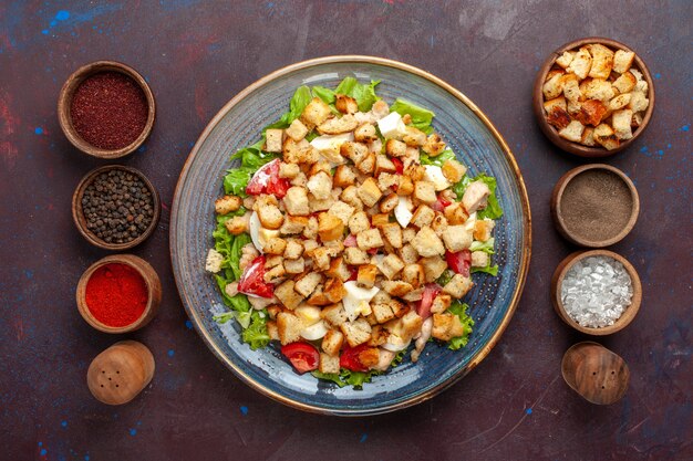 Vista superior saborosa salada caesar com temperos diferentes na superfície escura