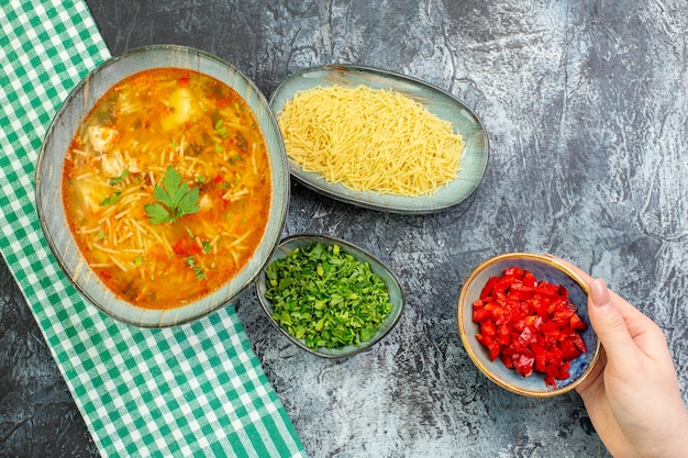 Vista superior saborosa sopa de aletria com verduras e aletria crua na mesa cinza claro