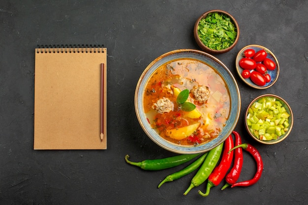 Vista superior saborosa sopa de almôndegas com verduras e pimenta na cor escura do prato de molho de mesa