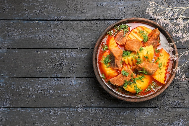 Vista superior saborosa sopa de carne com verduras e batatas na mesa escura