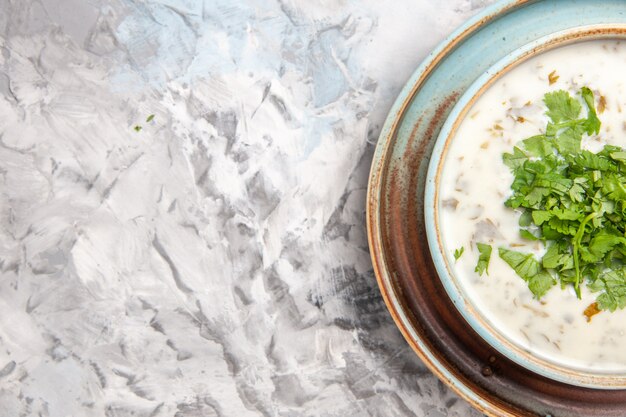 Vista superior saborosa sopa de iogurte dovga com verduras no chão branco prato de sopa de leite