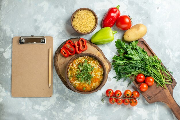 Vista superior saborosa sopa de vegetais com verduras e vegetais frescos em comida de sopa de refeição de vegetais de parede branca