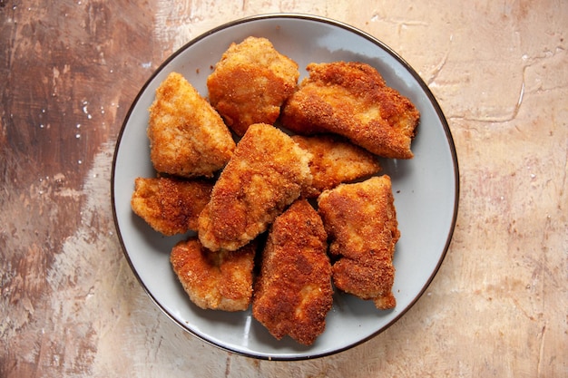 Vista superior saborosas asas de frango dentro do prato na superfície marrom hambúrguer refeição almoço sanduíche comida jantar batatas fritas carne
