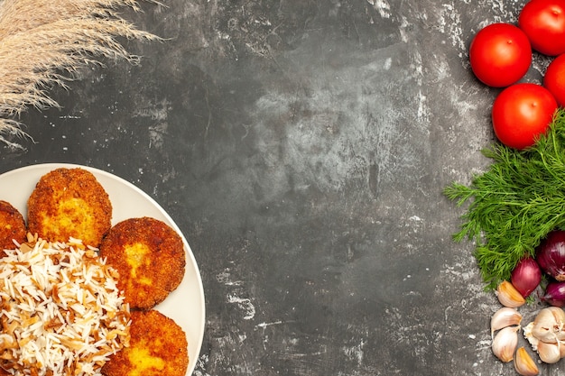 Vista superior saborosas costeletas fritas com arroz cozido em prato de superfície cinza foto de carne